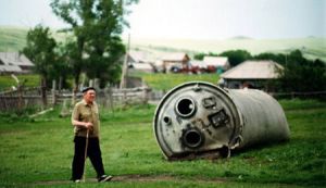 Hombre paseando junto a los restos de un cohete en un pueblecito del Altái. Foto: Jonas Bendiksen